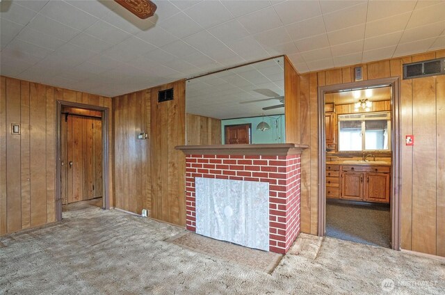 1257 S Ridgewood Ave, Tacoma, WA 98405 - unfurnished living room with a sink, wood walls, a fireplace, and carpet flooring