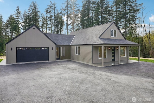 view of front facade featuring an attached garage, a shingled roof, aphalt driveway, and a porch