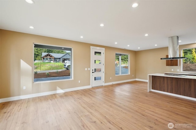 unfurnished living room with light wood finished floors, plenty of natural light, and recessed lighting