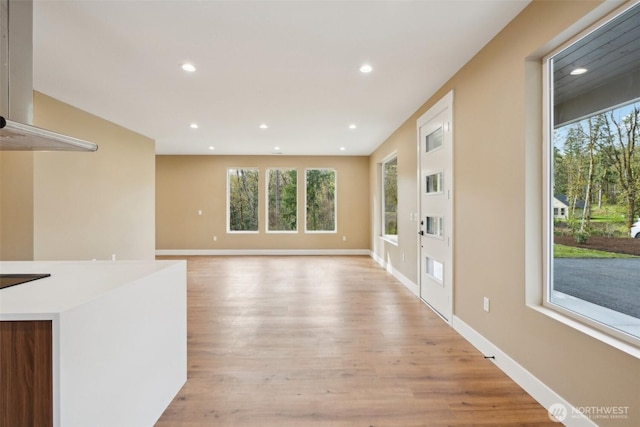 unfurnished living room with light wood-style floors, baseboards, plenty of natural light, and recessed lighting