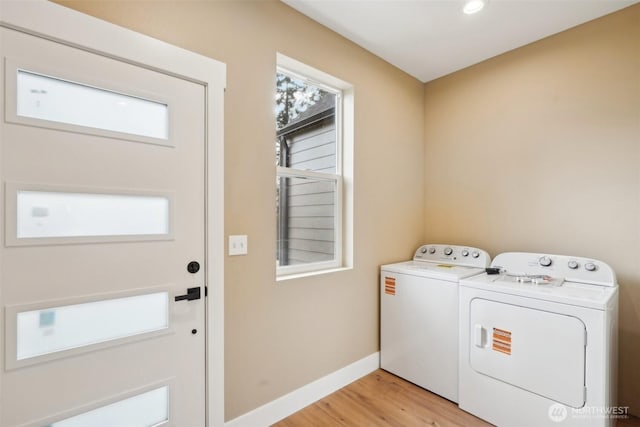 washroom featuring laundry area, separate washer and dryer, light wood finished floors, and baseboards