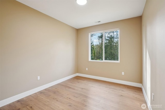 unfurnished room featuring light wood-type flooring, baseboards, and visible vents