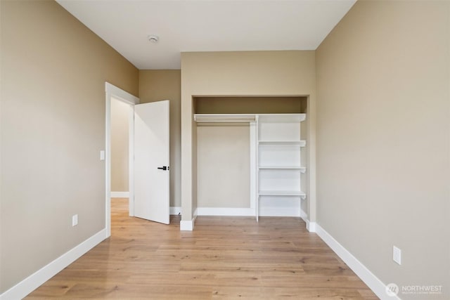 unfurnished bedroom featuring a closet, baseboards, and light wood-style floors