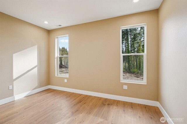 empty room featuring light wood-style floors, baseboards, and recessed lighting