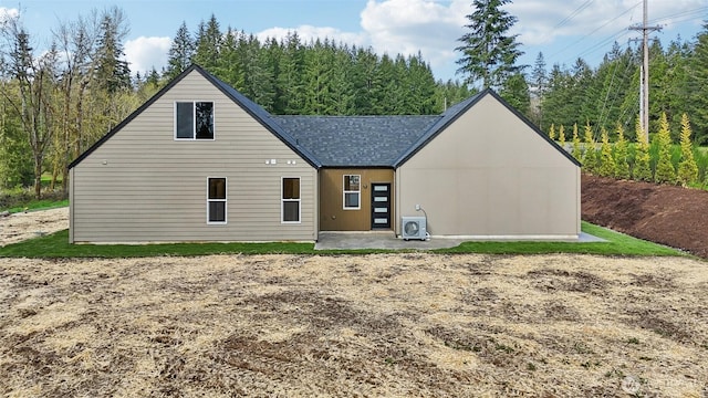 rear view of property with a shingled roof and a patio