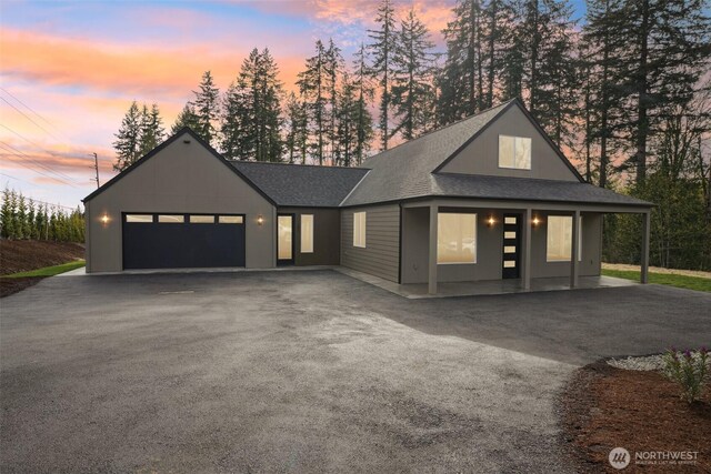 view of front facade featuring a garage, driveway, and roof with shingles