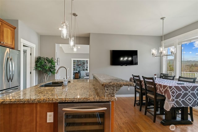 107 Springhill Dr, East Wenatchee, WA 98802 - kitchen with freestanding refrigerator, brown cabinetry, beverage cooler, a sink, and wood finished floors