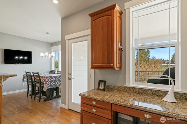 107 Springhill Dr, East Wenatchee, WA 98802 - kitchen featuring stone counters, a notable chandelier, light wood-style floors, and brown cabinets