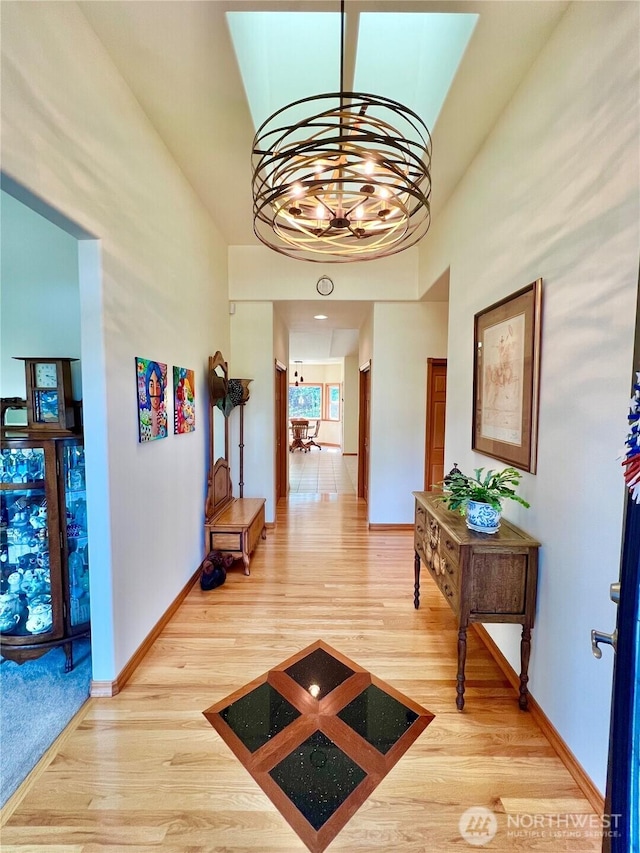 hallway featuring baseboards, a chandelier, and wood finished floors