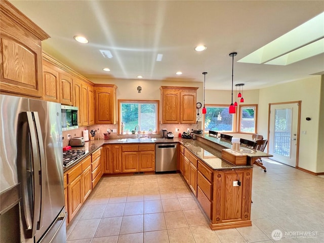 kitchen with recessed lighting, stainless steel appliances, dark stone countertops, decorative light fixtures, and a peninsula