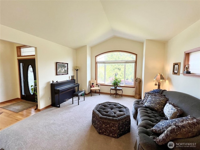 living room featuring baseboards, lofted ceiling, and carpet