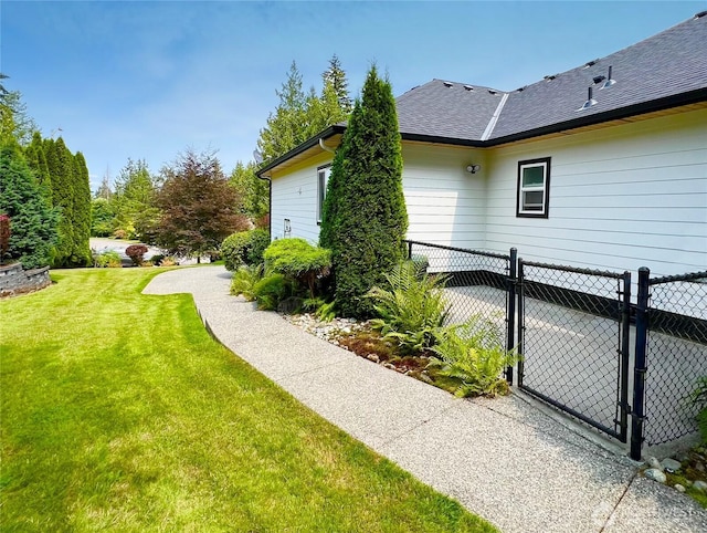 view of property exterior with a gate, a yard, roof with shingles, and fence
