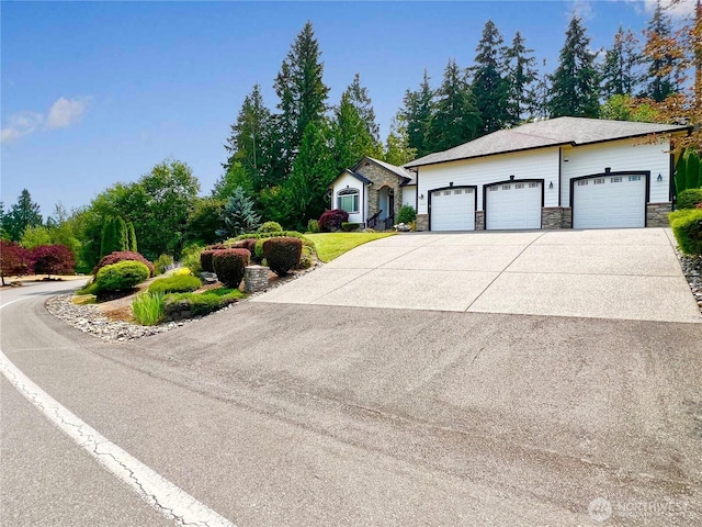 single story home featuring an attached garage, stone siding, and concrete driveway