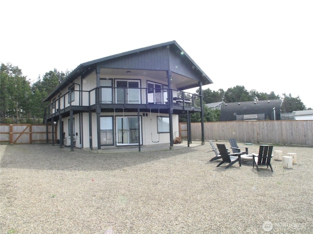 rear view of property featuring fence, a fire pit, and a balcony