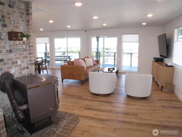 living area featuring light wood-style flooring, a wood stove, baseboards, and recessed lighting