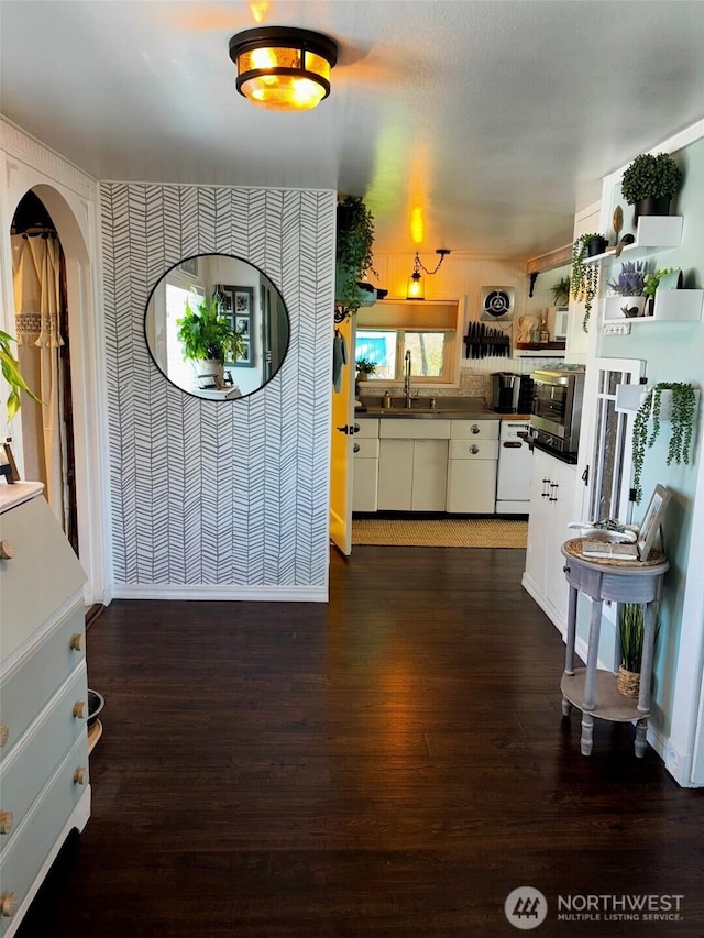 4216 N Pl, Seaview, WA 98644 - kitchen featuring dark countertops, a sink, wallpapered walls, white cabinets, and dark wood-type flooring