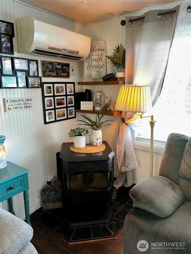 4216 N Pl, Seaview, WA 98644 - sitting room featuring wooden walls, wood finished floors, a wood stove, and a wall unit AC