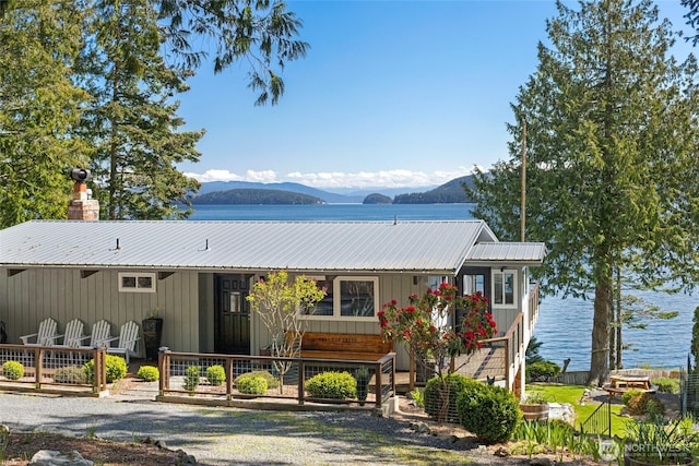 162 Sea Ranch Rd, Lopez Island, WA 98261 - view of front facade featuring a deck with water view, a chimney, metal roof, and board and batten siding