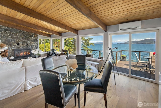 162 Sea Ranch Rd, Lopez Island, WA 98261 - dining space featuring a stone fireplace, a wall mounted air conditioner, light wood finished floors, and a water view