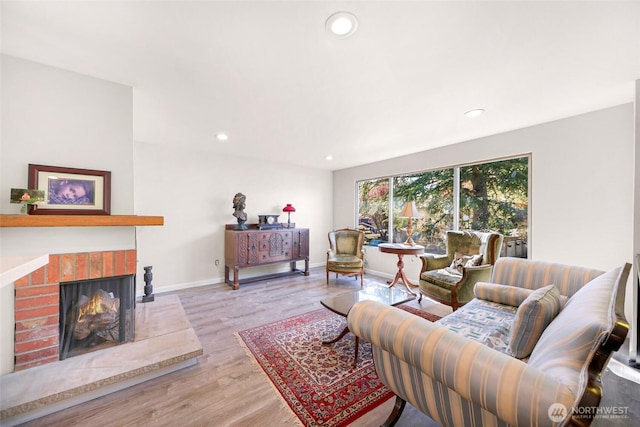 living area featuring baseboards, a brick fireplace, wood finished floors, and recessed lighting