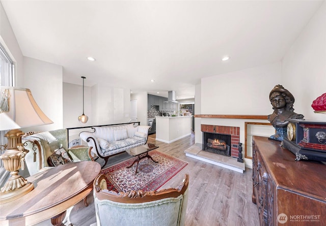 living room featuring light wood-style flooring, a fireplace, and recessed lighting