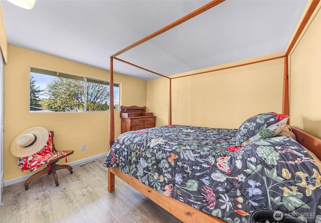 bedroom with wood finished floors, visible vents, and baseboards
