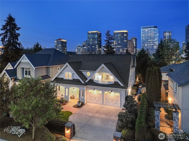 view of front of house featuring an attached garage, driveway, and a view of city lights