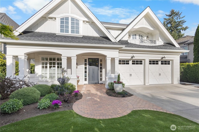view of front of home featuring board and batten siding, covered porch, roof with shingles, a garage, and concrete driveway