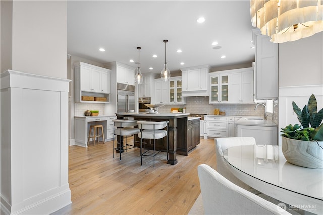 kitchen with decorative backsplash, a breakfast bar area, appliances with stainless steel finishes, a center island, and white cabinetry