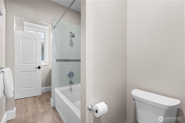 bathroom with tub / shower combination, baseboards, wood finished floors, and toilet
