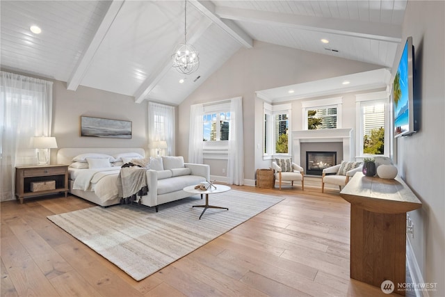 bedroom featuring light wood-style floors, multiple windows, beamed ceiling, and a glass covered fireplace