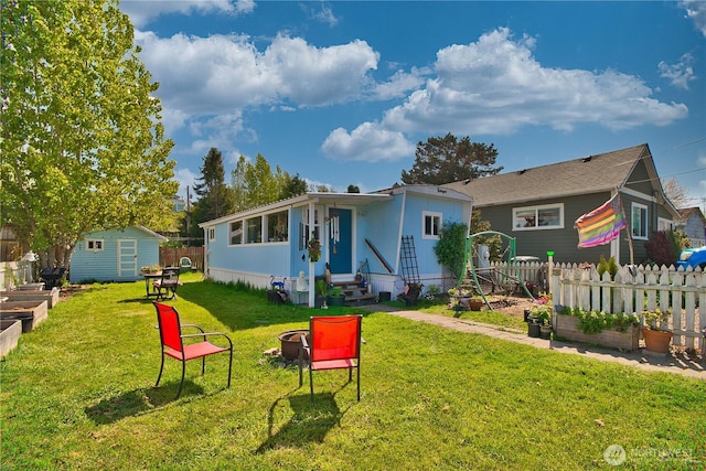 rear view of property featuring an outdoor structure, fence, a shed, a vegetable garden, and entry steps