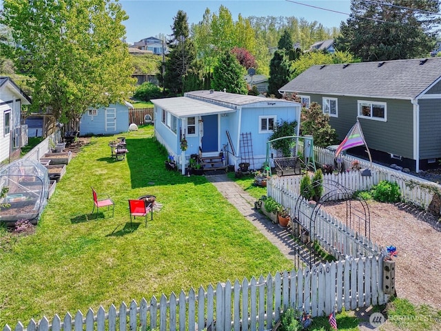 view of front of property with entry steps, an outdoor structure, a fenced backyard, and a front yard