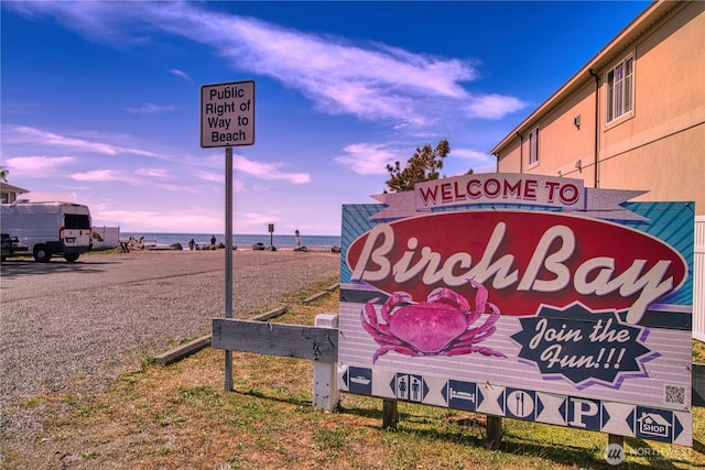 community sign featuring a view of the beach and a water view