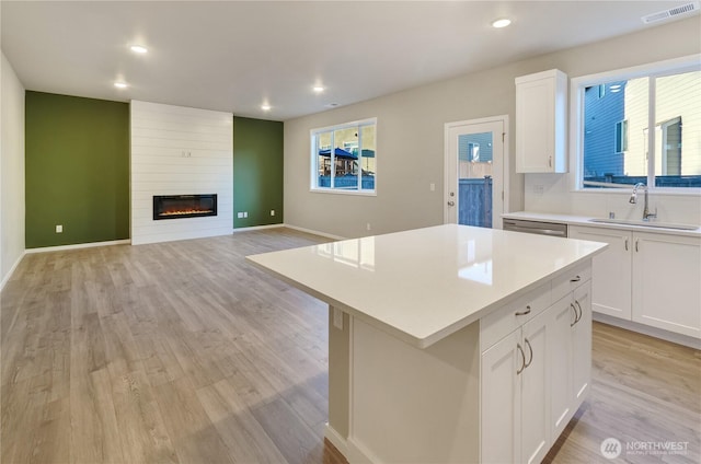 18218 37th Ave E, Tacoma, WA 98446 - kitchen featuring light wood-style flooring, visible vents, a kitchen island, light countertops, and a sink