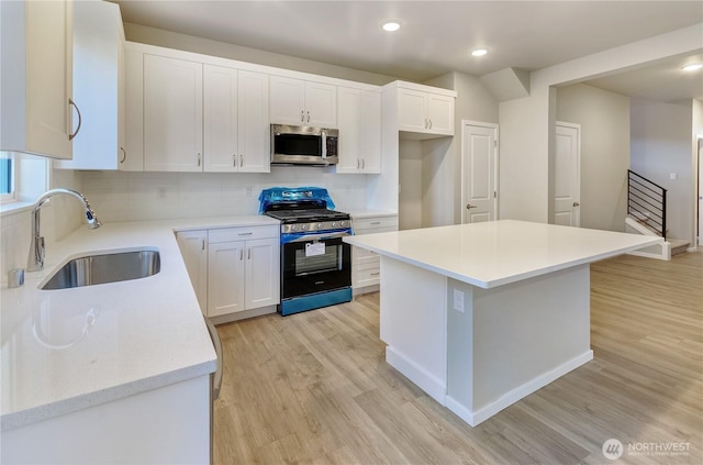 18218 37th Ave E, Tacoma, WA 98446 - kitchen with light wood-type flooring, stainless steel microwave, a sink, range with gas stovetop, and decorative backsplash