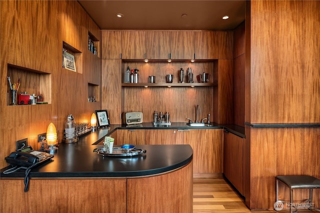 bar with light wood finished floors, a sink, and wet bar
