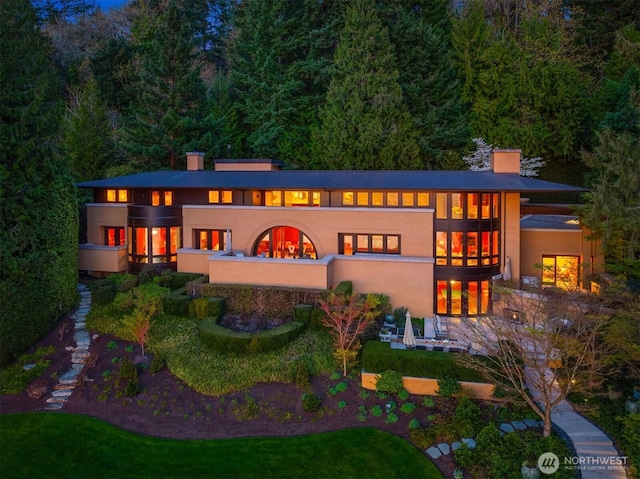 back of house featuring french doors, a chimney, and stucco siding