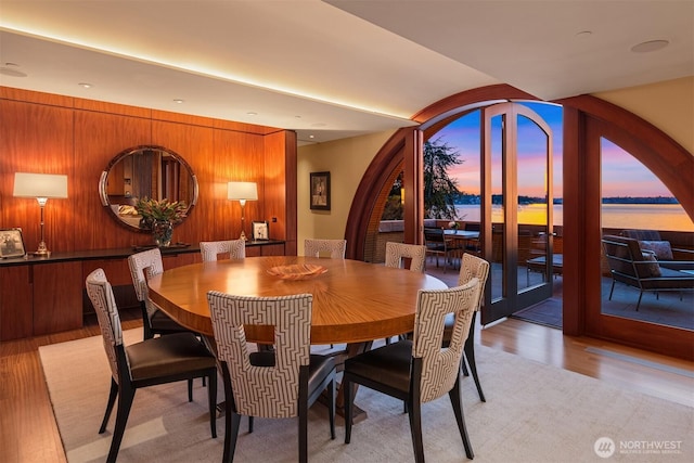 dining area with wood walls and light wood-type flooring