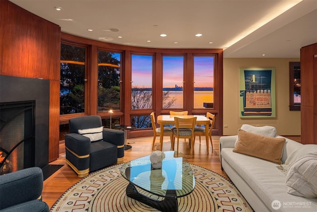 living room featuring a water view, recessed lighting, light wood finished floors, and a fireplace