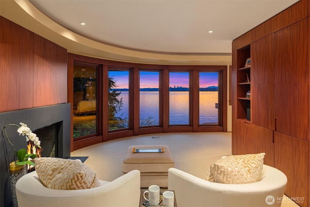 living room featuring a water view, recessed lighting, a large fireplace, and built in features