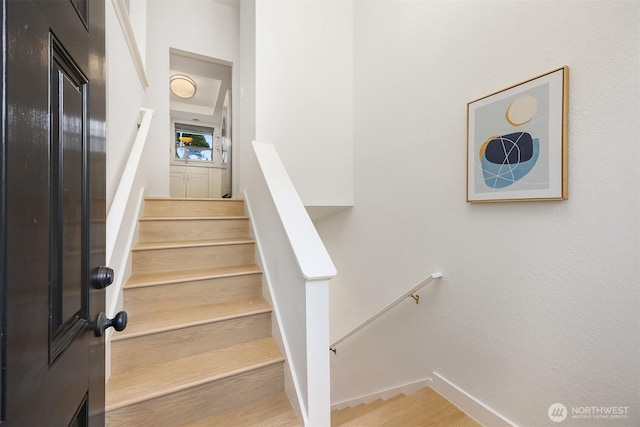 staircase featuring wood finished floors and baseboards