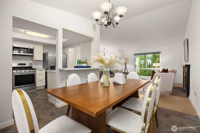 dining space with a chandelier, dark tile patterned flooring, and baseboards