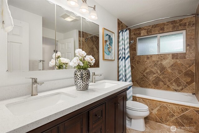 bathroom with tiled shower / bath, toilet, and double vanity