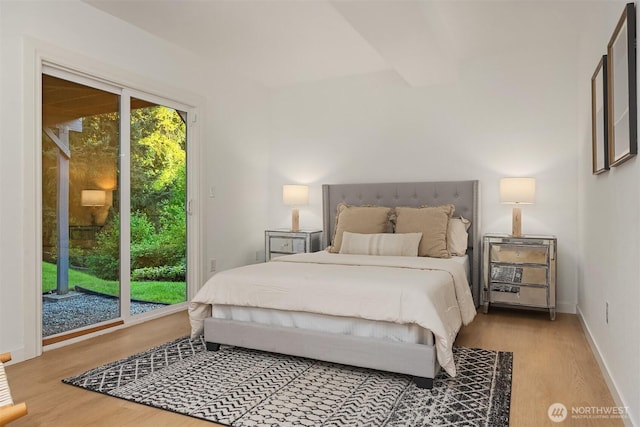 bedroom with access to outside, wood finished floors, and baseboards