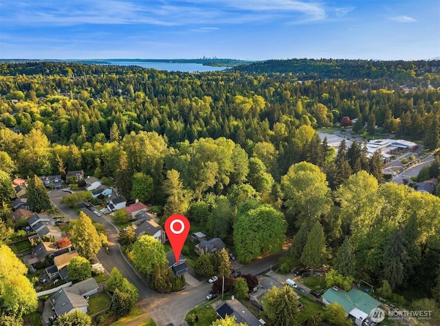 aerial view of property's location with a forest, a nearby body of water, and nearby suburban area