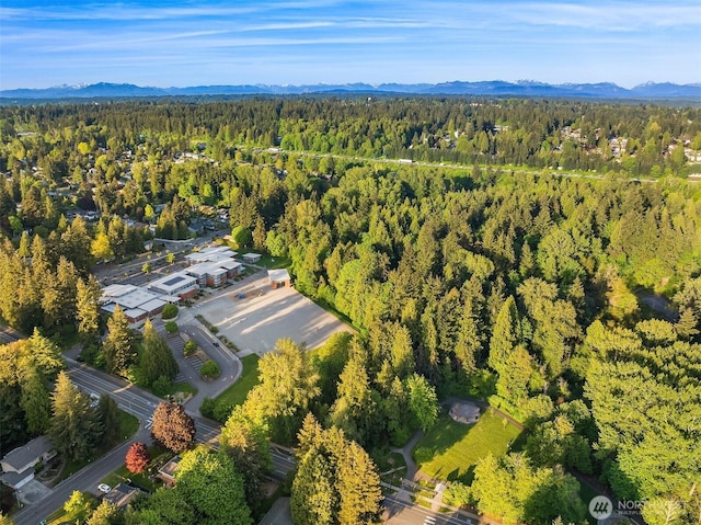 aerial view of property and surrounding area with a forest and mountains