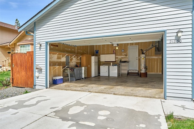 21850 SE 271st Pl, Maple Valley, WA 98038 - garage featuring washer and dryer, strapped water heater, freestanding refrigerator, and concrete driveway