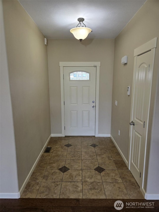 entryway featuring tile patterned floors, baseboards, and visible vents