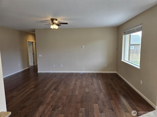 spare room with ceiling fan, baseboards, and dark wood finished floors